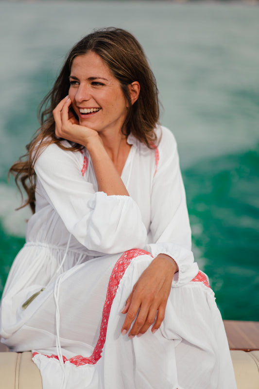 Michaela trägt ein luftig leichtes Sommerkleid von Carmensita. Das Maxikleid in weiß mit handverlesenen Veredelungen wird in Österreich hergestellt. Das lange Kleid aus Viskose ist hautfreundlich und der perfekte Begleiter durch deinen Tag.