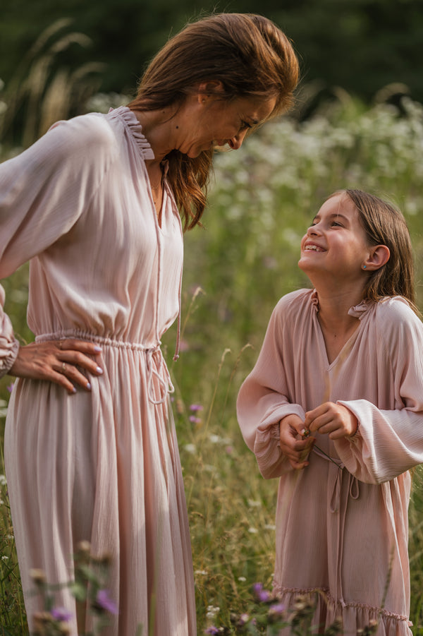 Mutter und Tochter im angesagten Mini Me Partnerlook. Die Mutter trägt ein luftig leichtes bodenlanges Sommerkleid in zartem Rosè. Die Tochter trägt ein knielanges Kleid im gleichen Rosè Farbton. Die Kleider sind aus reiner Viskose angenehm auf der Haut zu tragen. Carmensita | Sommerkleider made in Austria.